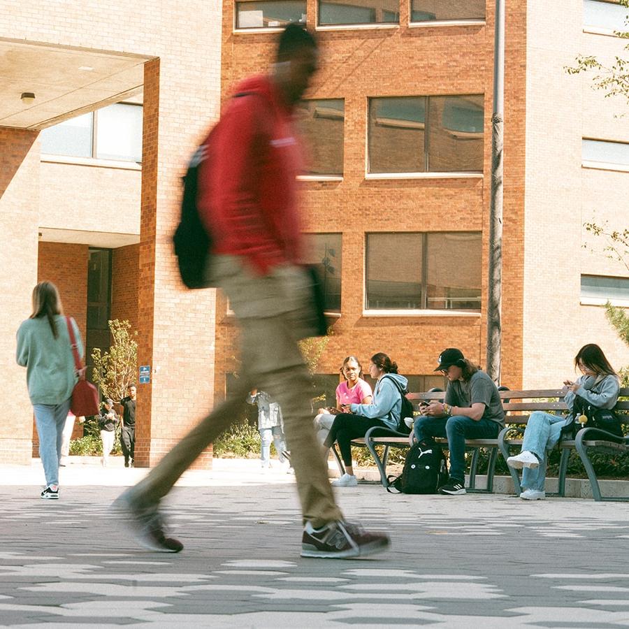 student in motion walking through the Quad